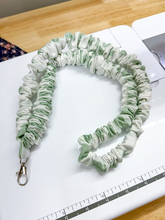 Green scrunchie on a white surface with a ruler for scale
