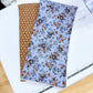 Two fabric swatches, one brown and one with a floral pattern on a white surface.