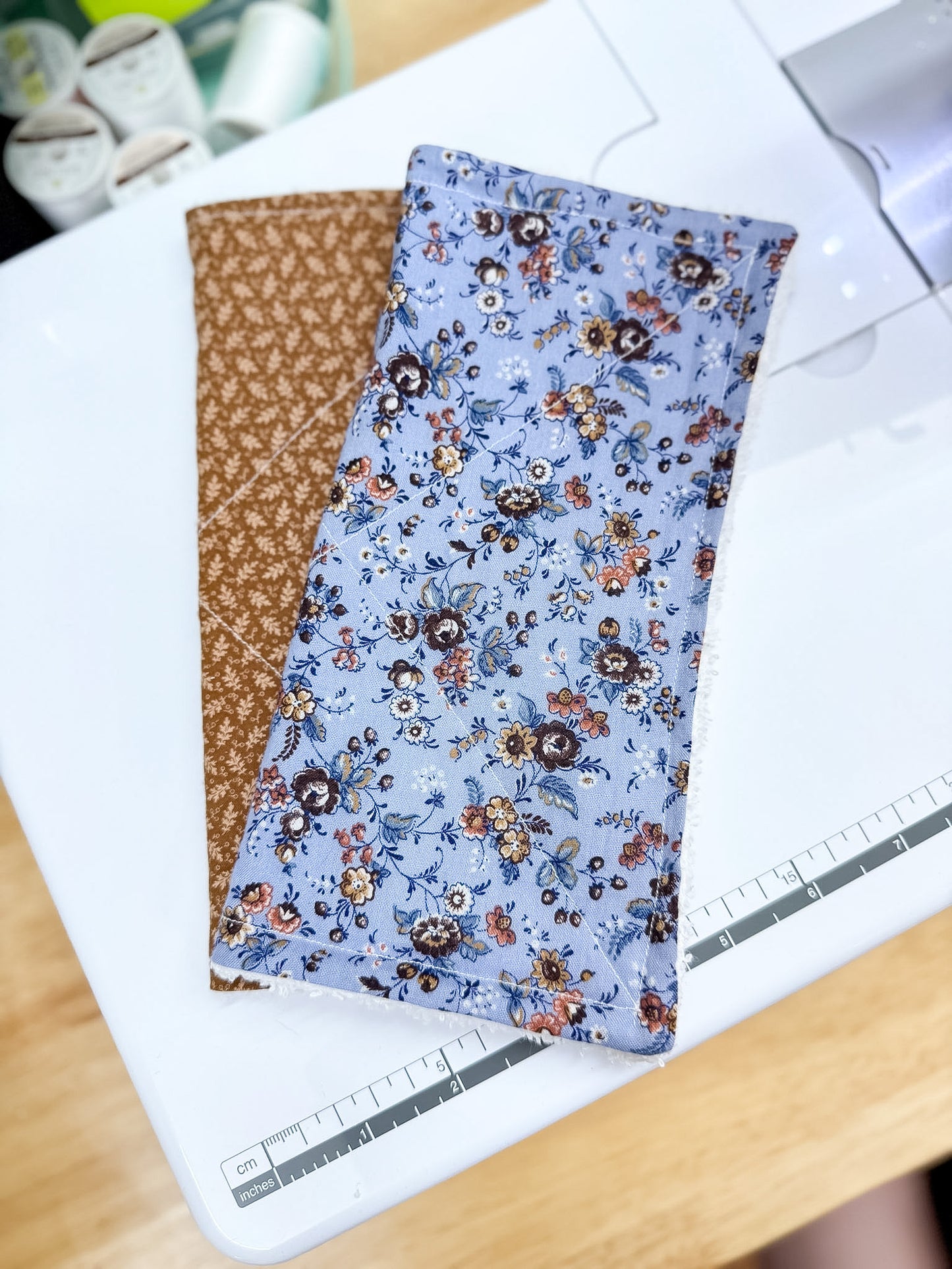 Two fabric swatches, one brown and one with a floral pattern on a white surface.