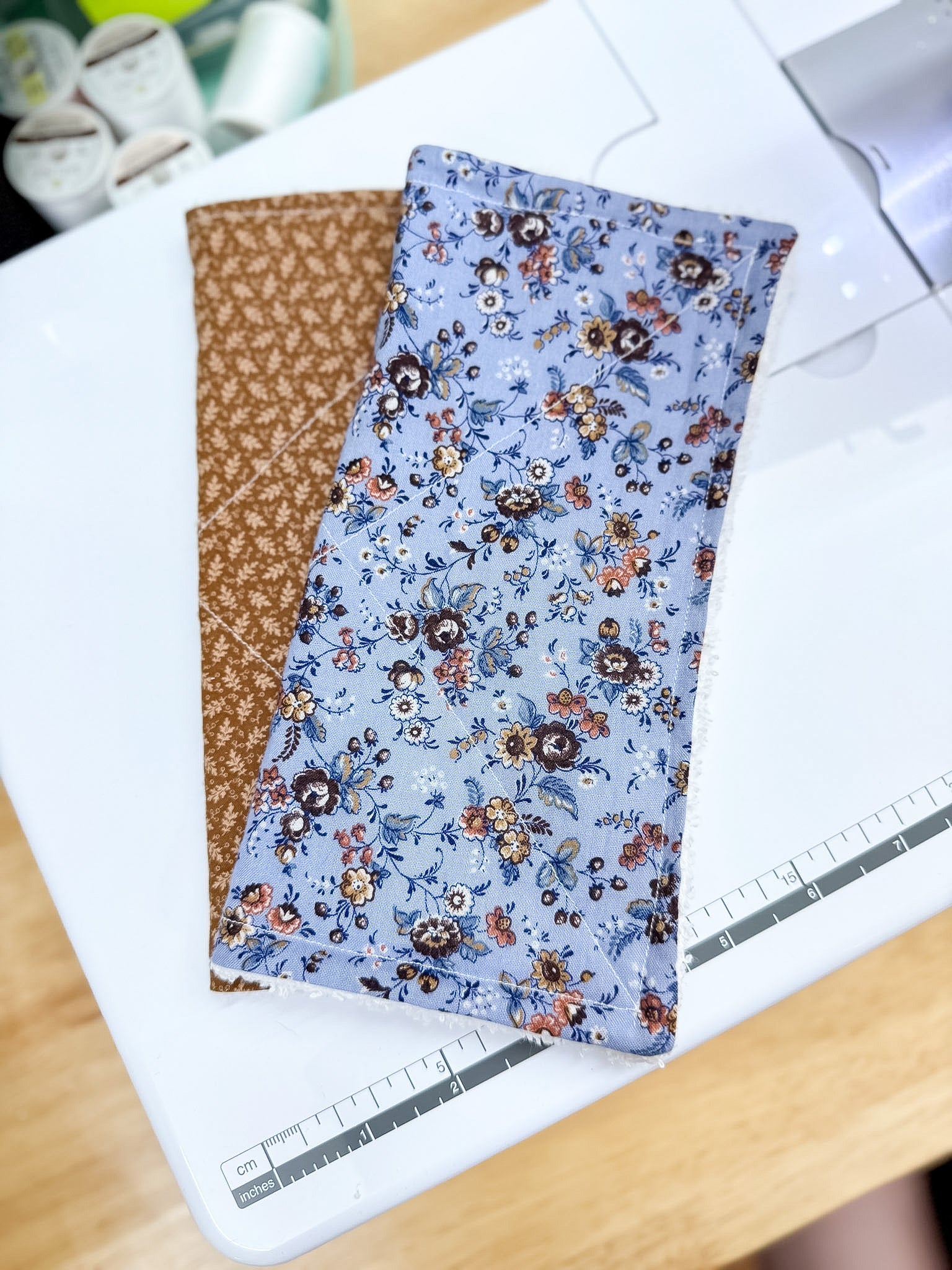 Two fabric swatches, one brown and one with a floral pattern on a white surface.