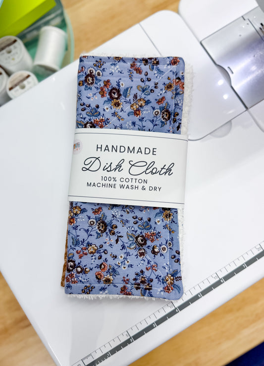 Pack of handmade dish cloths with floral pattern on a cutting board.