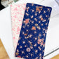 Two floral-patterned fabric swatches on a white surface with a ruler in the background.