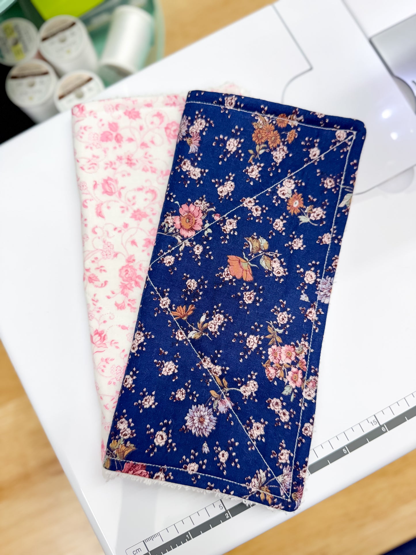 Two floral-patterned fabric swatches on a white surface with a ruler in the background.