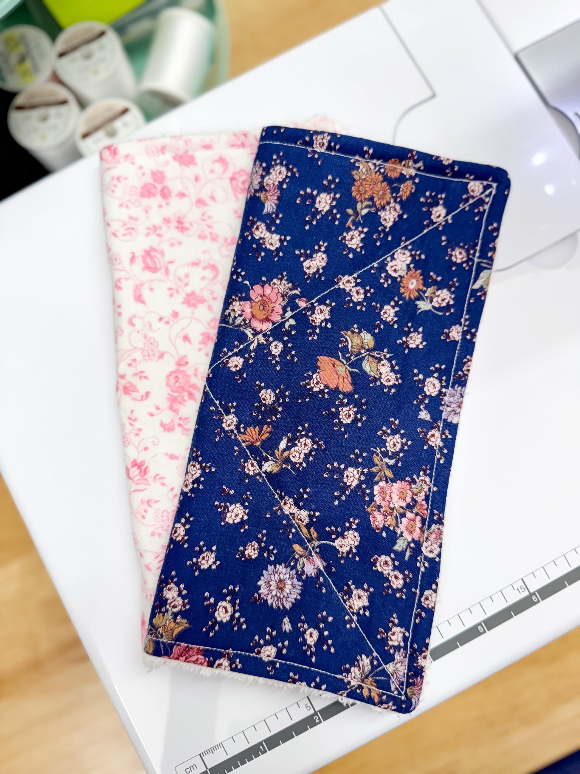 Two floral-patterned fabric swatches on a white surface with a ruler in the background.