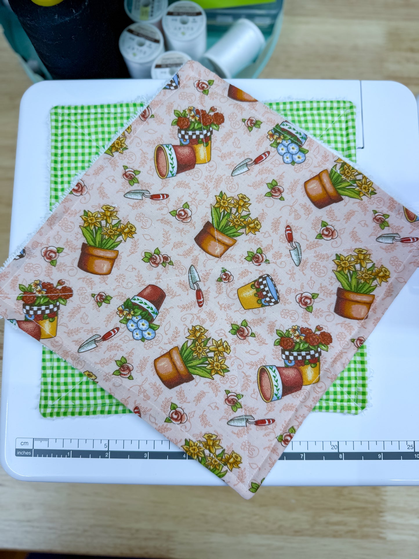 Fabric with garden-themed pattern on a cutting mat with a ruler