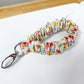 Colorful keychain with floral pattern on a white surface with ruler for scale.