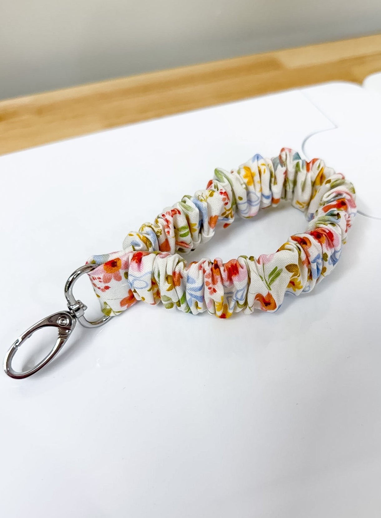 Colorful keychain with floral pattern on a white surface with ruler for scale.