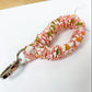 Floral patterned keychain on a white surface with a ruler for scale.