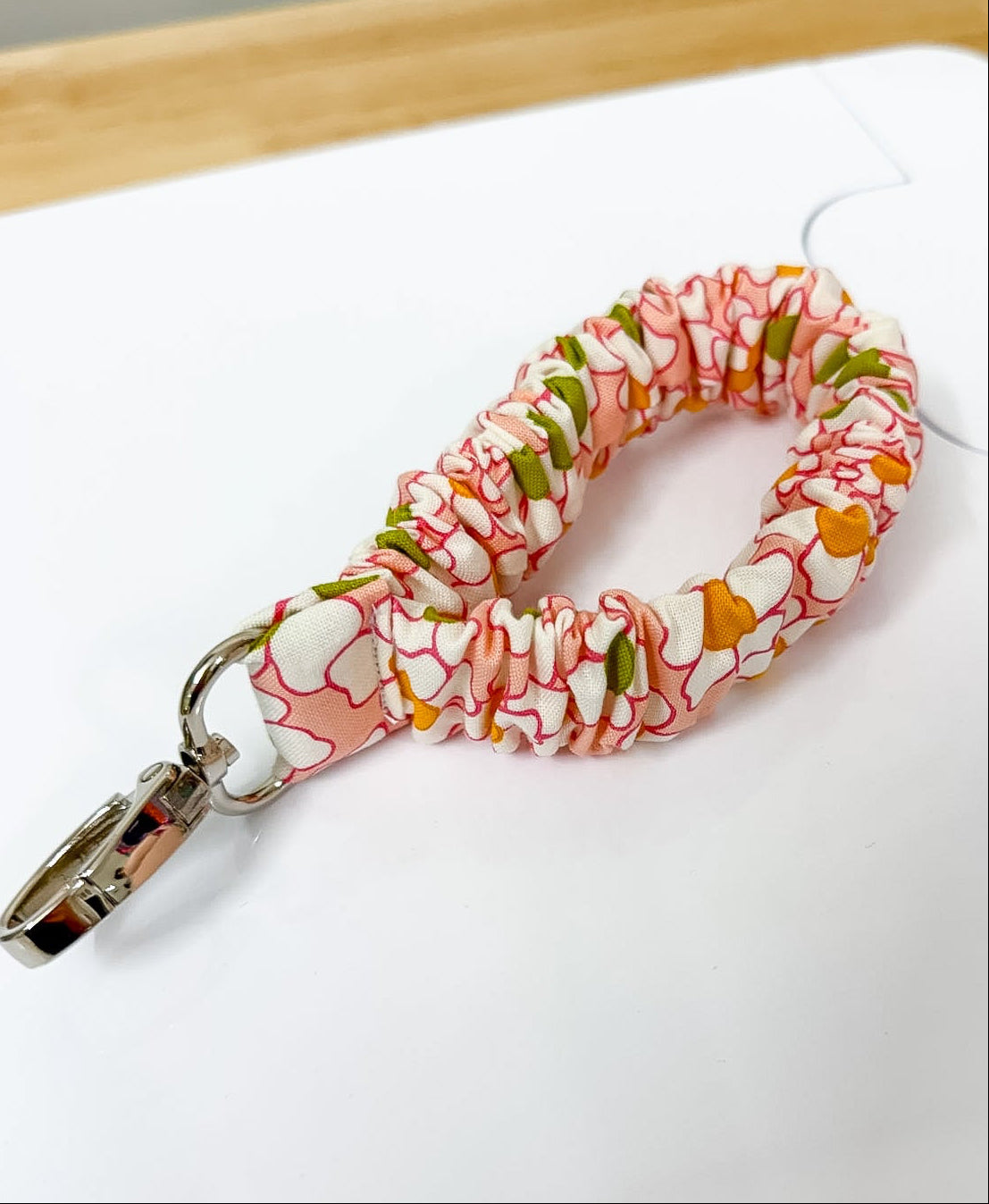 Floral patterned keychain on a white surface with a ruler for scale.