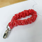 Red scrunchie keychain on a white surface with a ruler for scale.
