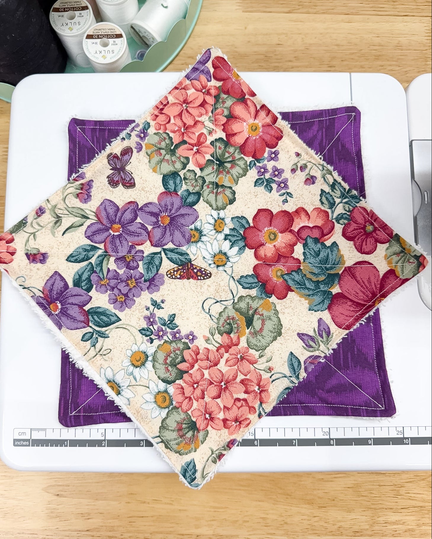 Floral fabric on a cutting mat with a ruler, on a wooden surface.