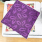 Purple fabric square with leaf pattern on a sewing machine
