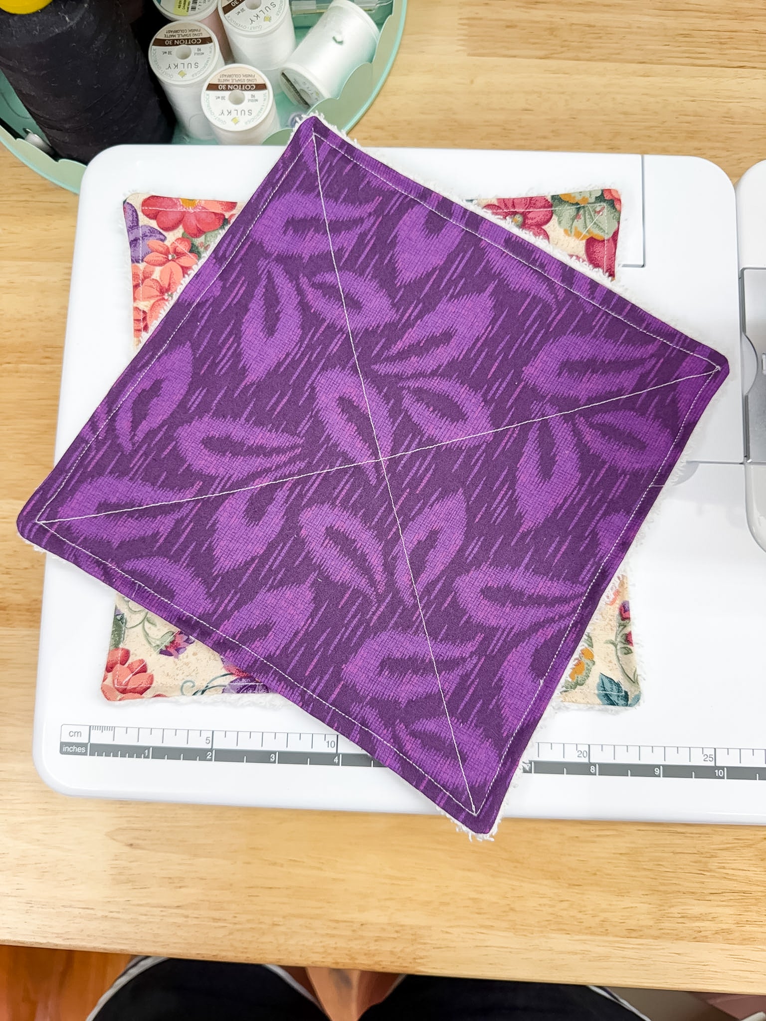 Purple fabric square with leaf pattern on a sewing machine