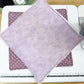 Purple fabric on a cutting mat with a ruler, on a wooden surface.
