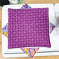 Purple patterned fabric on a white surface with colorful butterfly designs.