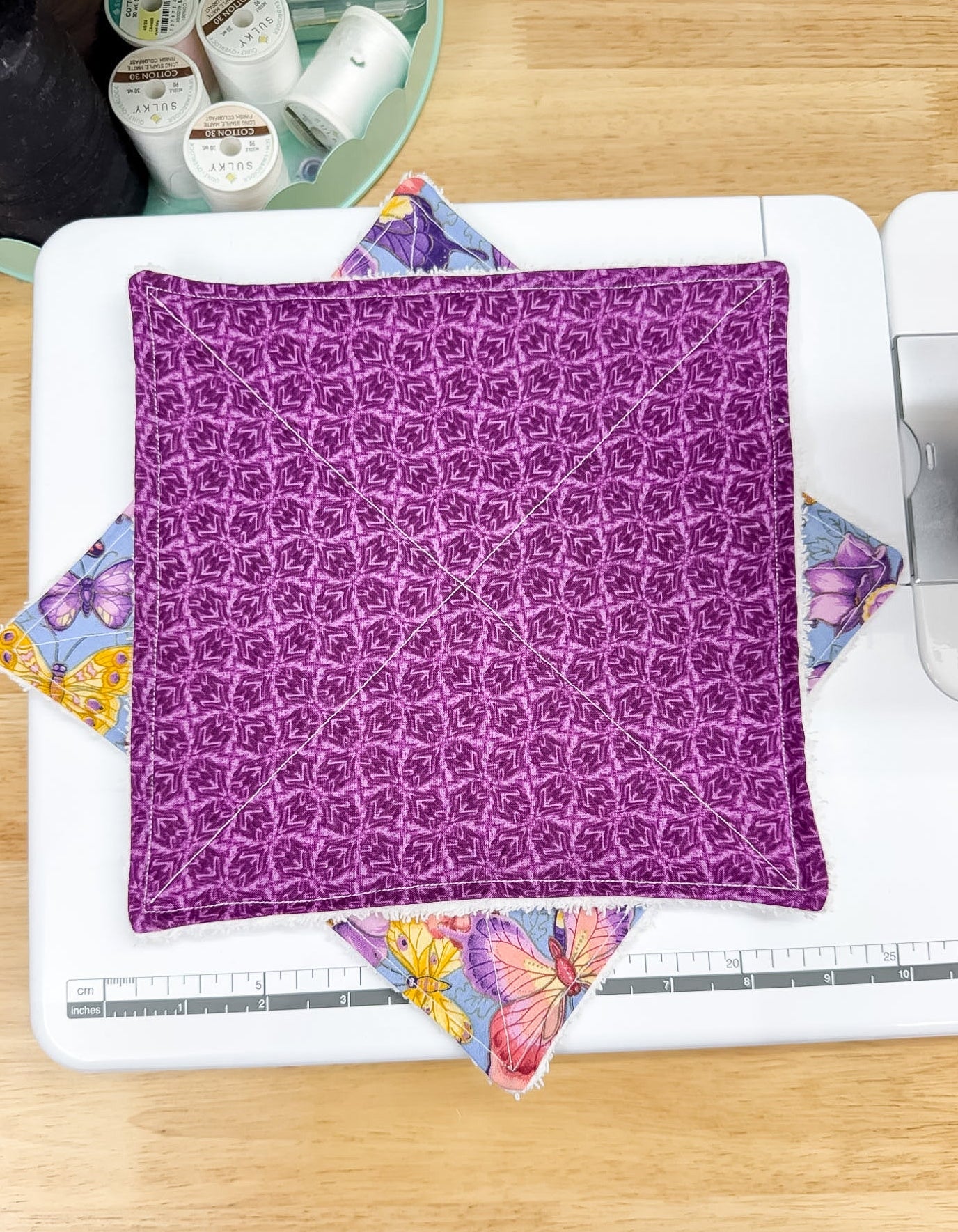 Purple patterned fabric on a white surface with colorful butterfly designs.