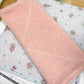 Pink fabric on a floral-patterned surface with a ruler for scale.
