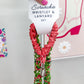 Hand holding a scrunchie wristlet and lanyard set with a decorative background.
