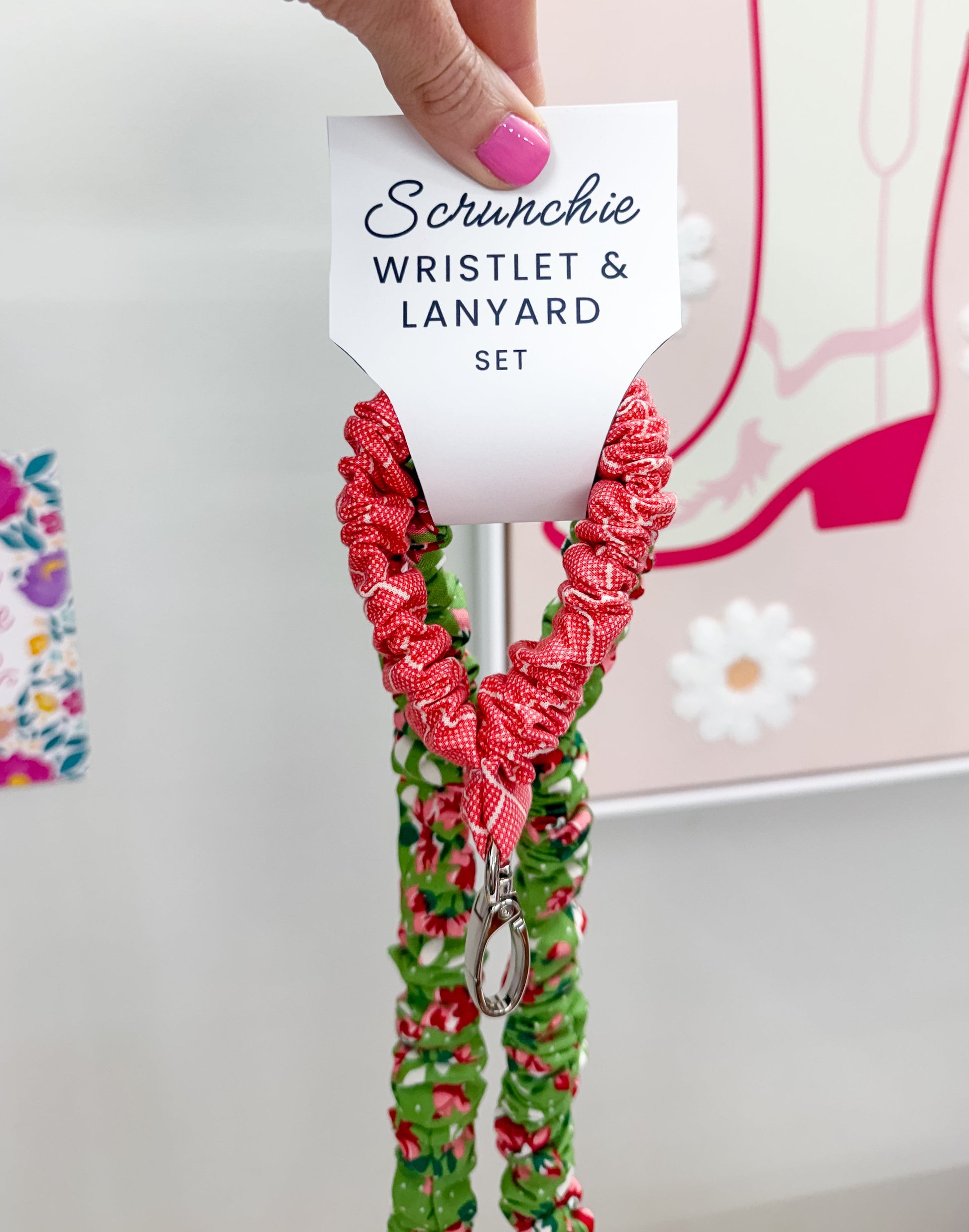 Hand holding a scrunchie wristlet and lanyard set with a decorative background.