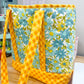 Floral-patterned bag with yellow straps on a wooden surface