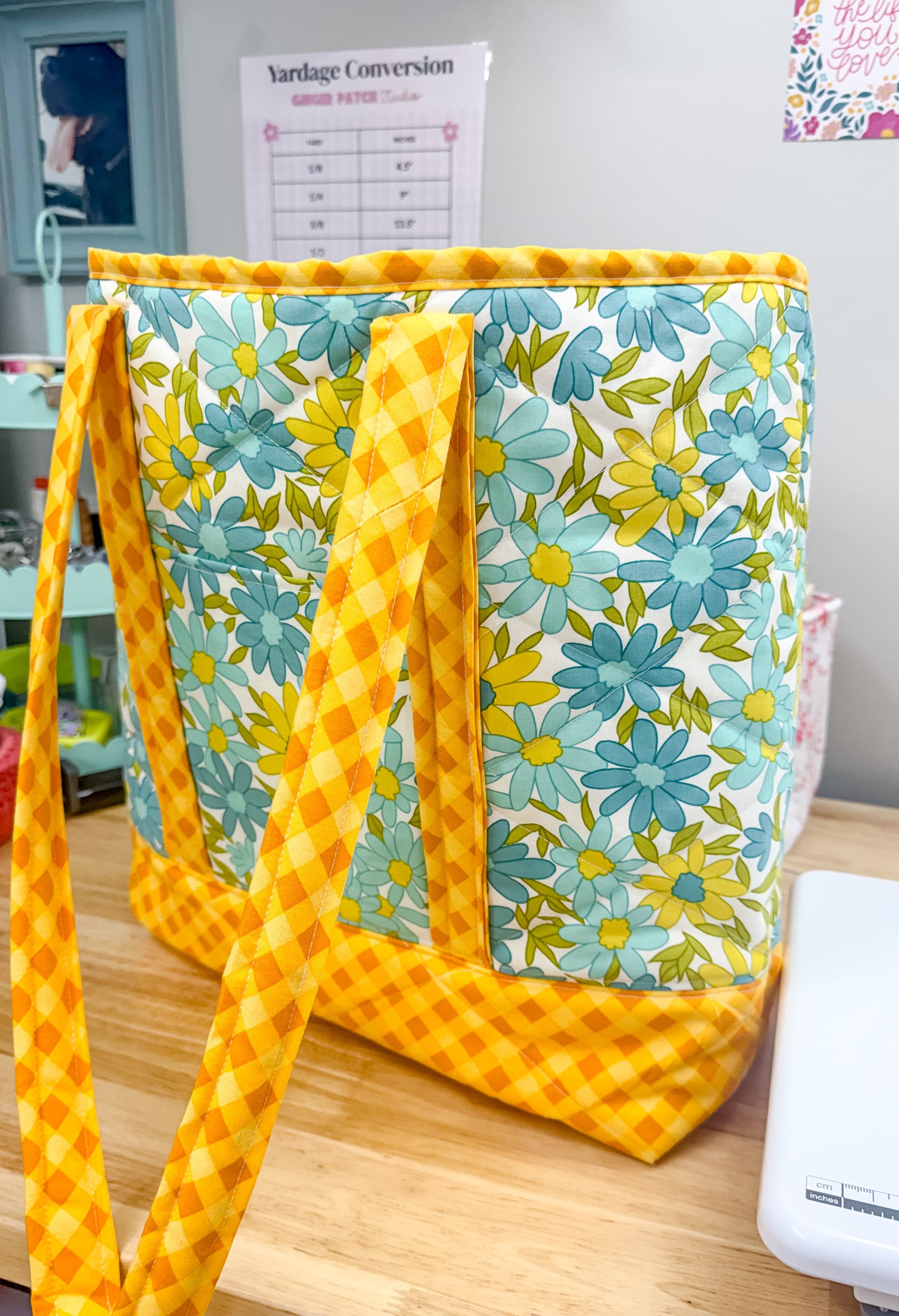Floral-patterned bag with yellow straps on a wooden surface