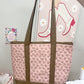 Handmade tote bag with pink floral pattern held above a sewing machine.