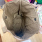 Brown fabric bag with black buttons on a wooden surface with various items in the background