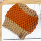Crocheted beanie with orange and brown gradient on a white surface