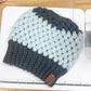 Knitted beanie with gray and light blue pattern on a wooden surface