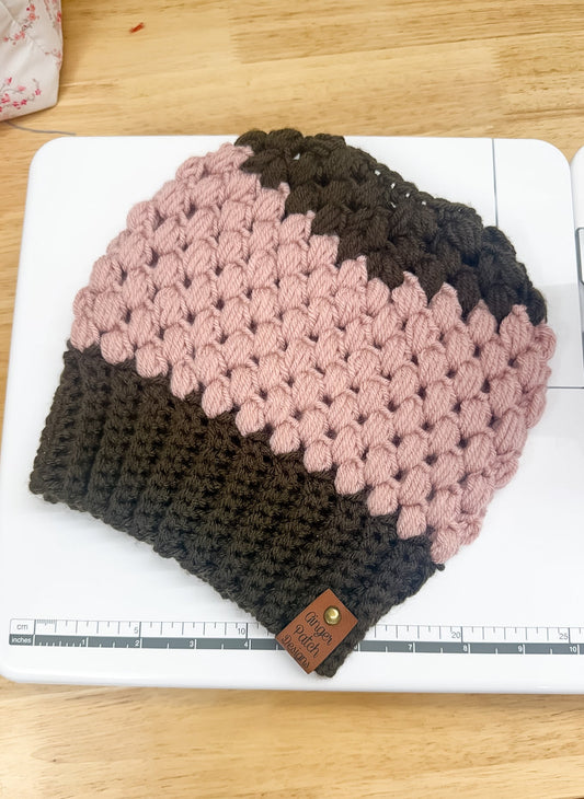 Knitted beanie with pink and brown gradient on a wooden surface