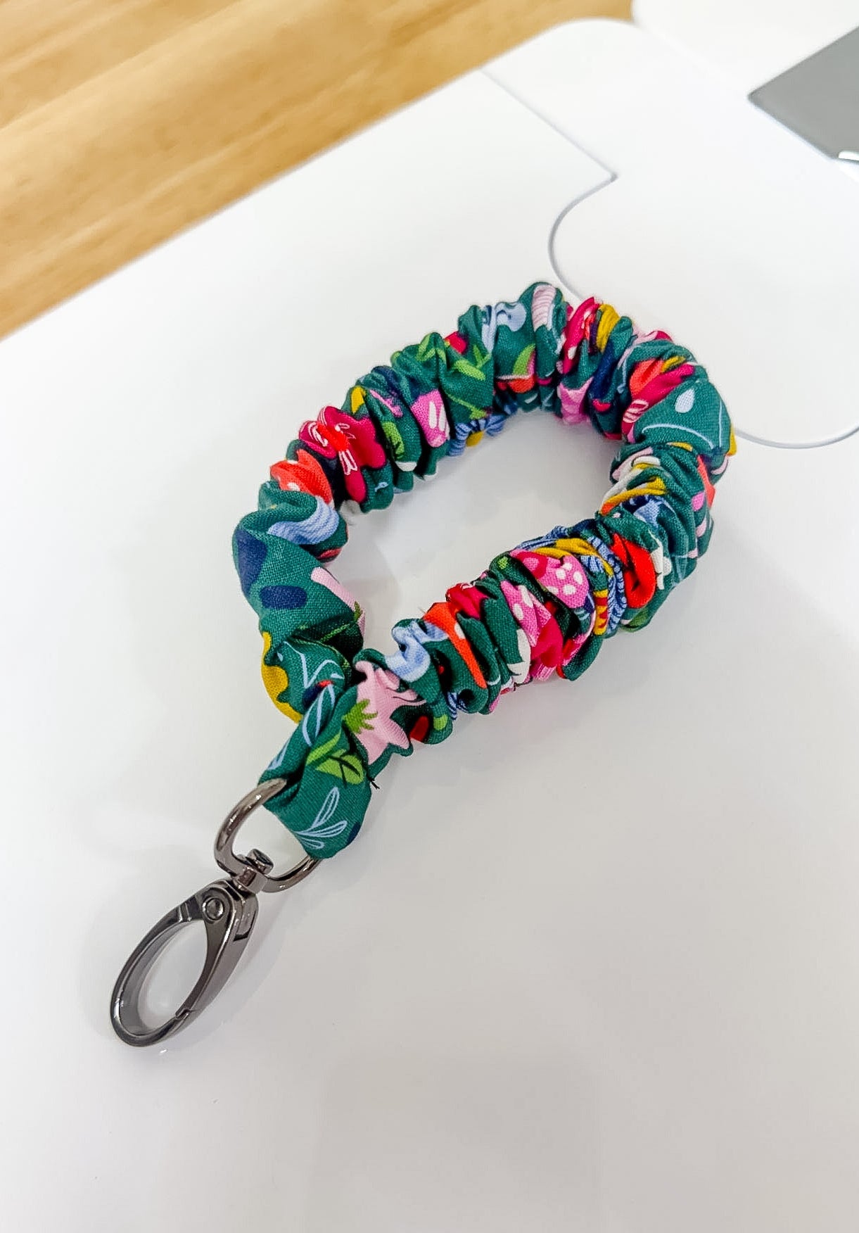 Multicolored scrunchie keychain on a white surface with a wooden background