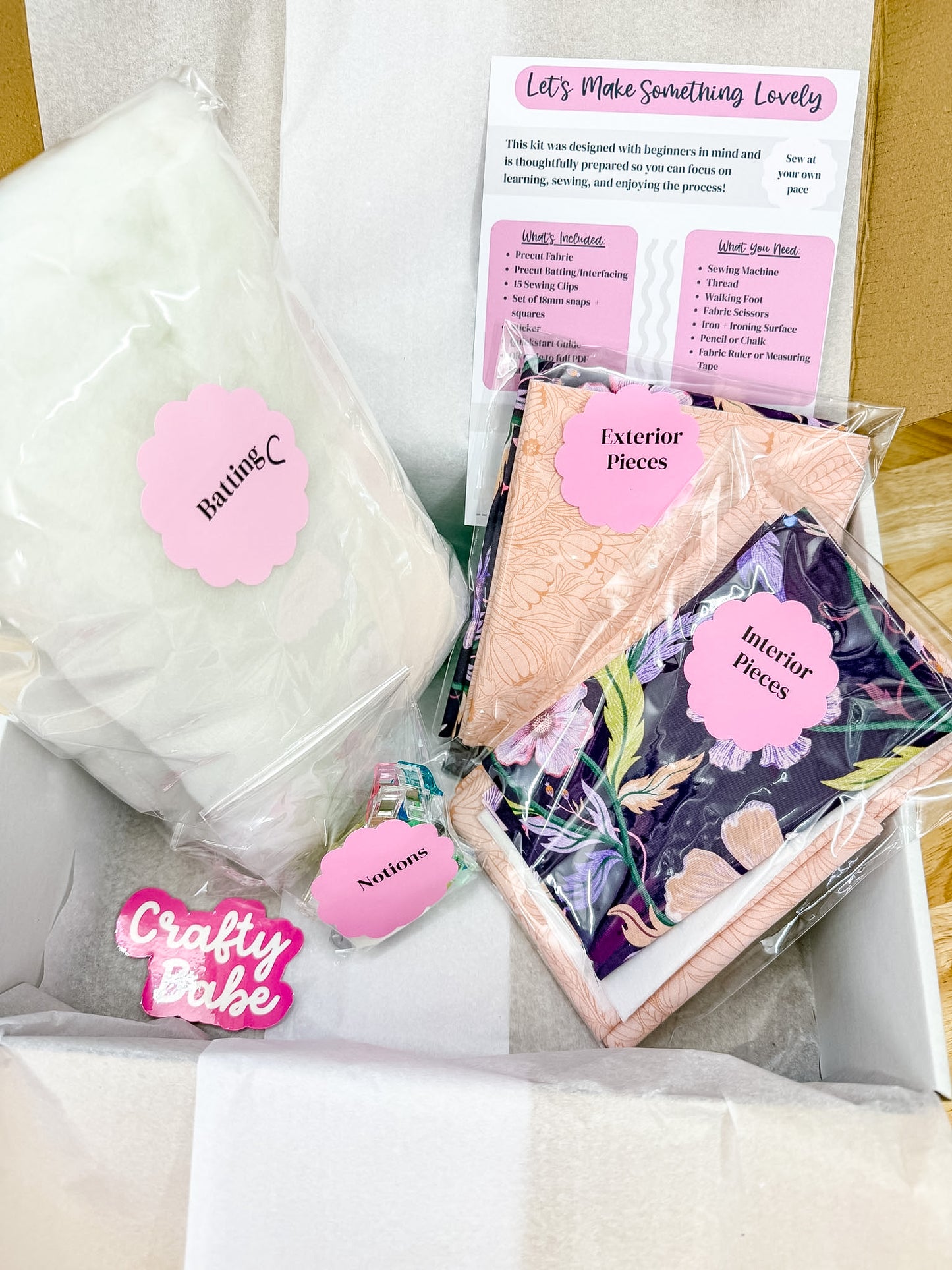 A curated craft kit box labeled 'Let's Make Something Lovely' by ButteryC, containing a large white fabric ball, patterned fabric pieces in peach and floral prints, a 'ButteryC' branded tag, and an instruction booklet.