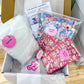 A cardboard box filled with sewing supplies, including a large white bag labeled 'Bulbs', floral fabric pieces in blue and pink, and a pink tag reading 'Crafty Baker'.