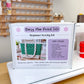 A boxed beginner sewing kit labeled 'Daisy Mae Pocket Tote' standing on a white machine on a wooden table, with a sewing supply rack blurred in the background.