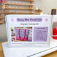 A white box labeled 'Daisy Mae Pocket Tote Beginner Sewing Kit' sits on a white sewing machine in a sewing room. The box shows a photo of a colorful quilted tote bag and lists included items such as pre-cut fabric, interfacing, sewing tips, and patterns.