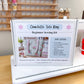 A sewing kit box labeled 'Charlotte Tote Bag Beginner Sewing Kit' displayed on a white sewing machine in a bright craft room with shelves of thread in the background.