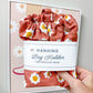 A hand holds a terracotta-colored fabric hanging bag holder with a white daisy print and a white paper label that reads 'Hanging Bag Holder for Grocery Bags.' The background shows a framed matching bag holder on a light gray wall.