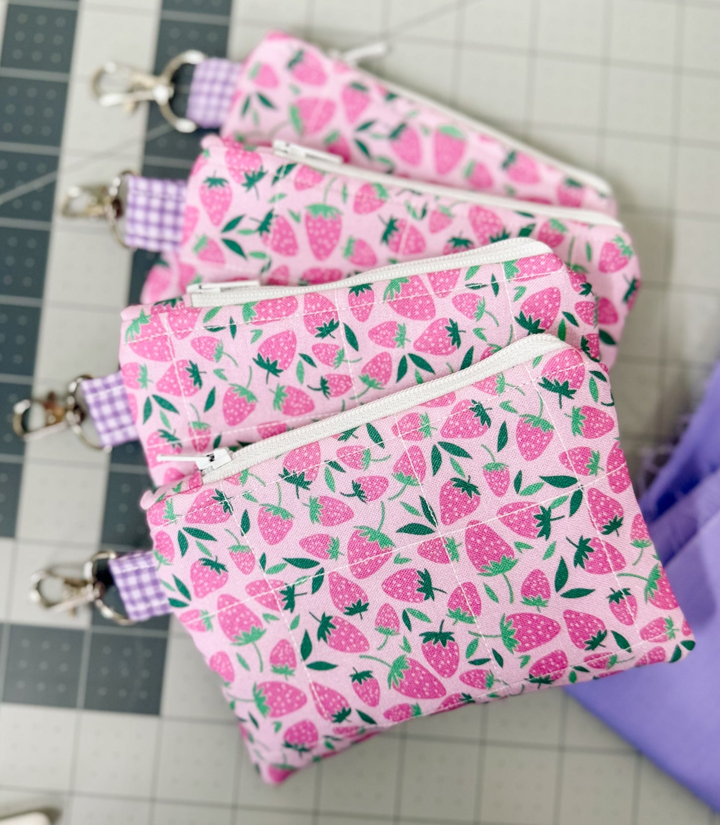 Set of pink fabric pouches with strawberry pattern on a cutting mat
