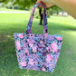 Floral patterned tote bag held by a hand outdoors on grass