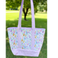 Floral patterned tote bag with purple accents on a grassy background